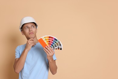 Photo of Portrait of young decorator with color palettes on beige background, space for text