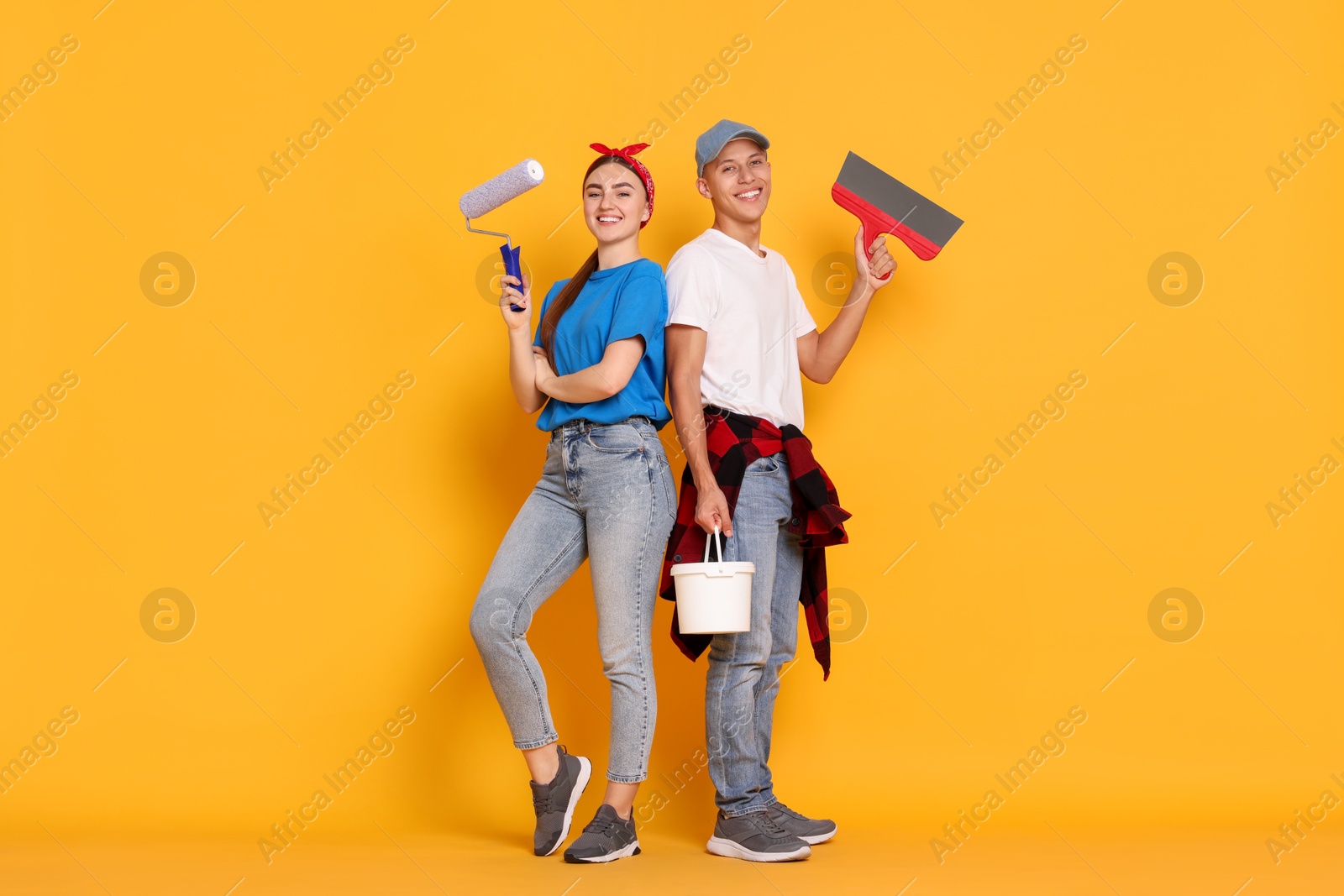 Photo of Professional decorator. Man and woman with different tools on orange background