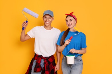 Photo of Professional decorator. Man and woman with different tools on orange background