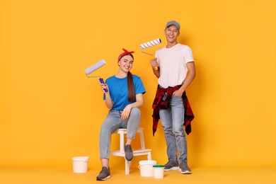 Photo of Professional decorator. Man and woman with different tools on orange background