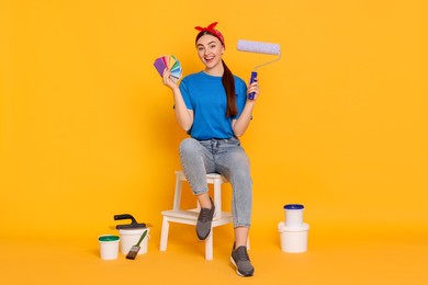 Photo of Young decorator with different tools on orange background