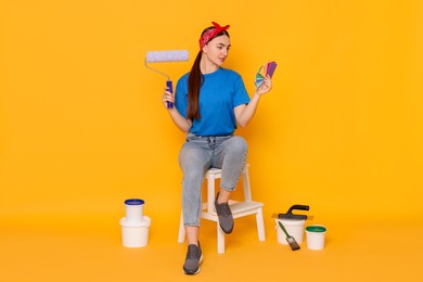 Photo of Young decorator with different tools on orange background