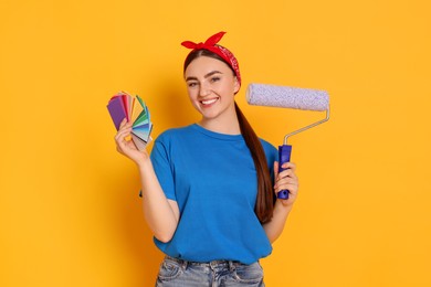 Photo of Portrait of young decorator with color palettes and paint roller on orange background