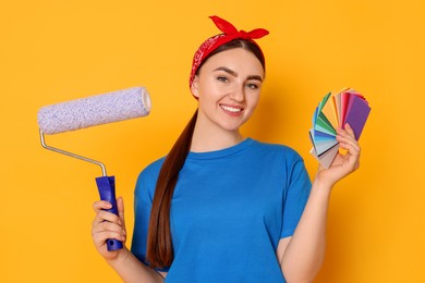 Photo of Portrait of young decorator with color palettes and paint roller on orange background