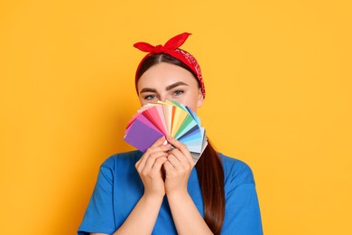 Photo of Portrait of young decorator with color palettes on orange background