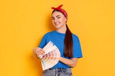 Photo of Portrait of young decorator with color palettes on orange background