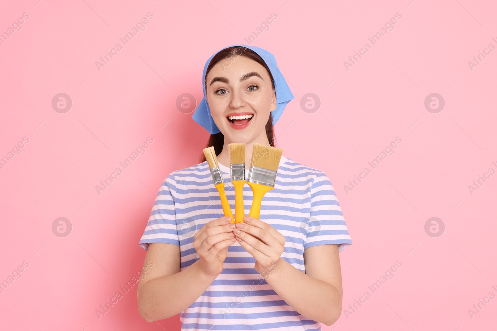 Photo of Portrait of young decorator with brushes on pink background