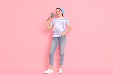 Photo of Young decorator with putty knife on pink background