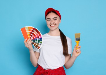 Portrait of young decorator with color palettes and brush on light blue background