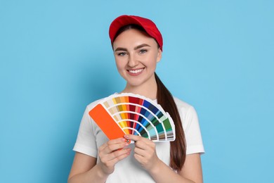 Photo of Portrait of young decorator with color palettes on light blue background