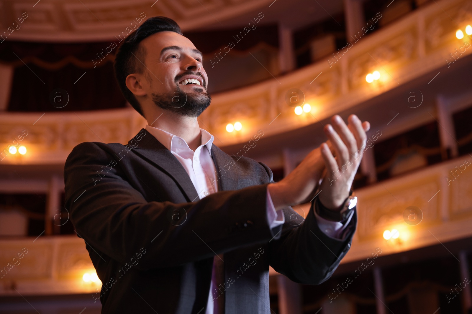 Photo of Portrait of happy man applauding in theatre, low angle view