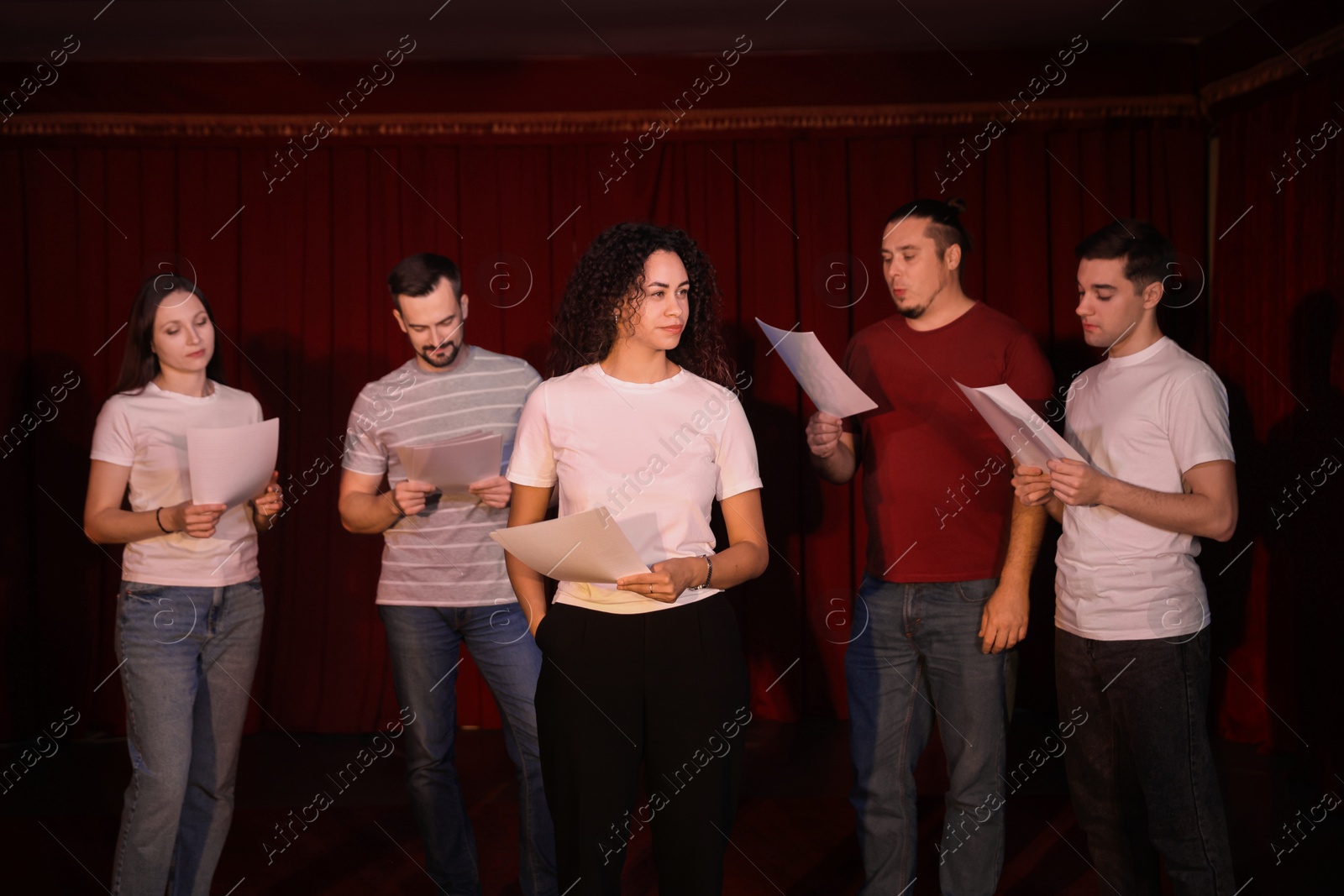 Photo of Professional actors with their scripts rehearsing in theatre