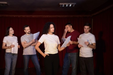 Photo of Professional actors with their scripts rehearsing in theatre