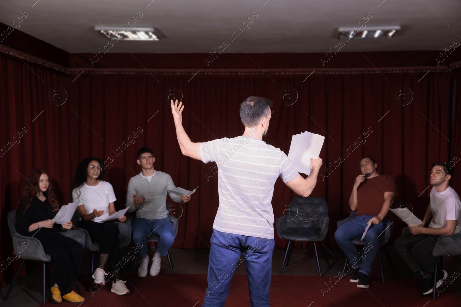 Photo of Professional actors with their scripts rehearsing in theatre