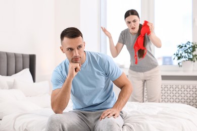 Photo of Puzzled wife finding mistress bra and unfaithful husband in bedroom, selective focus