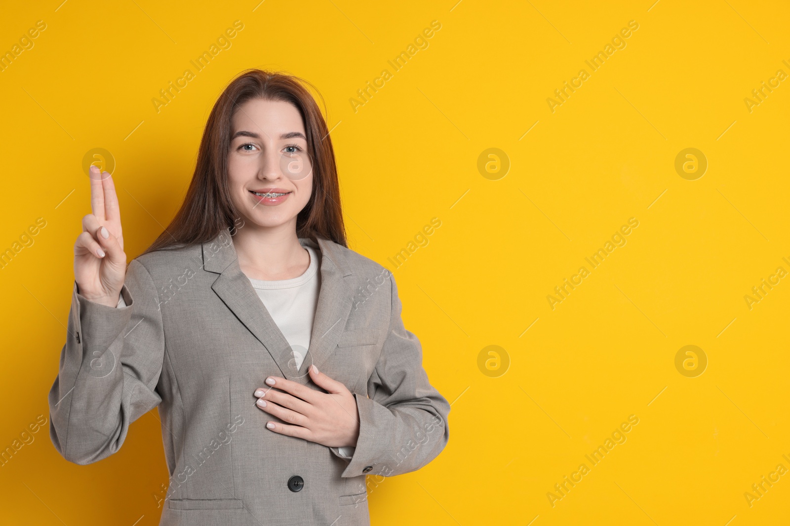 Photo of Woman showing oath gesture on orange background, space for text. Making promise