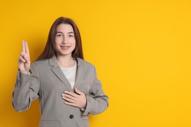 Photo of Woman showing oath gesture on orange background, space for text. Making promise