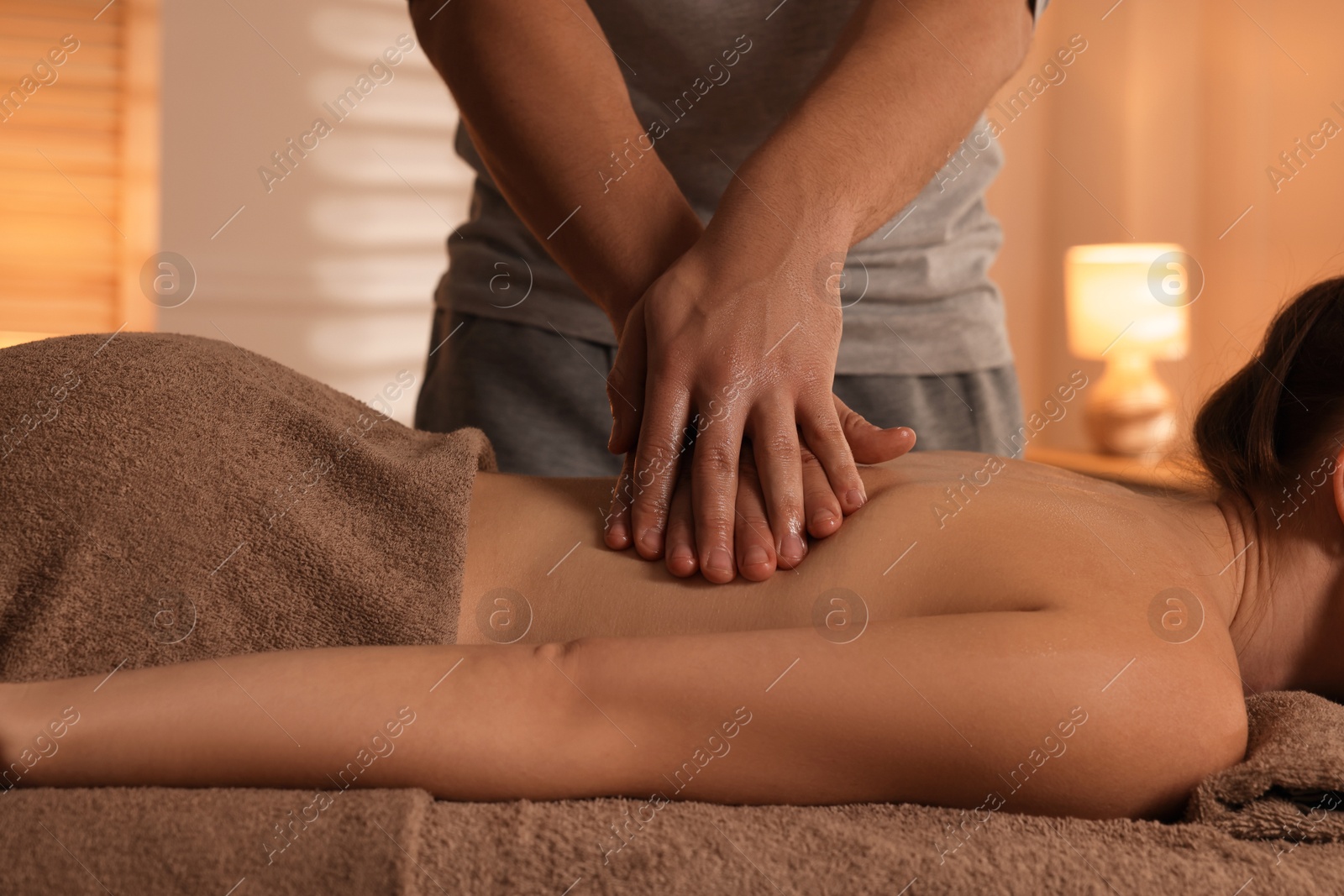 Photo of Osteopath massaging woman's back on couch indoors, closeup. Manual therapy