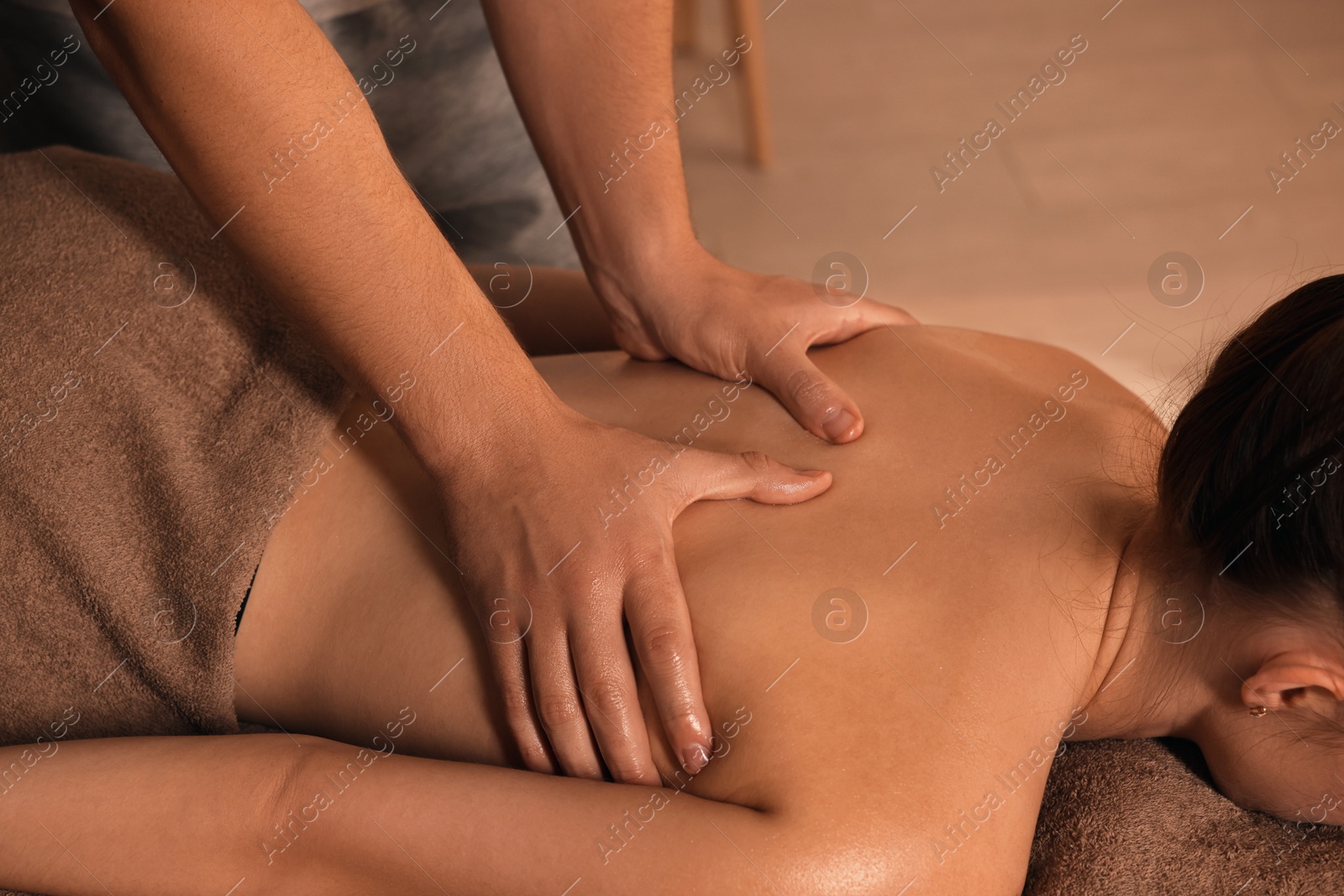 Photo of Osteopath massaging woman's back on couch indoors, closeup. Manual therapy