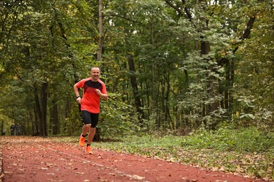 Photo of Athletic man running in park, space for text