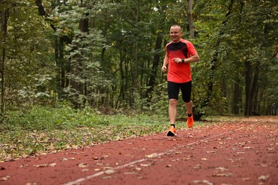 Photo of Athletic man running in park, space for text