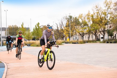 Photo of Group of athletic people riding bicycles outdoors, space for text