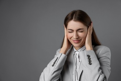 Photo of Woman covering her ears on grey background, space for text