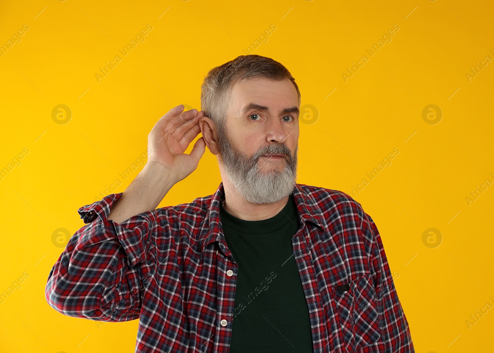 Photo of Senior man showing hand to ear gesture on orange background