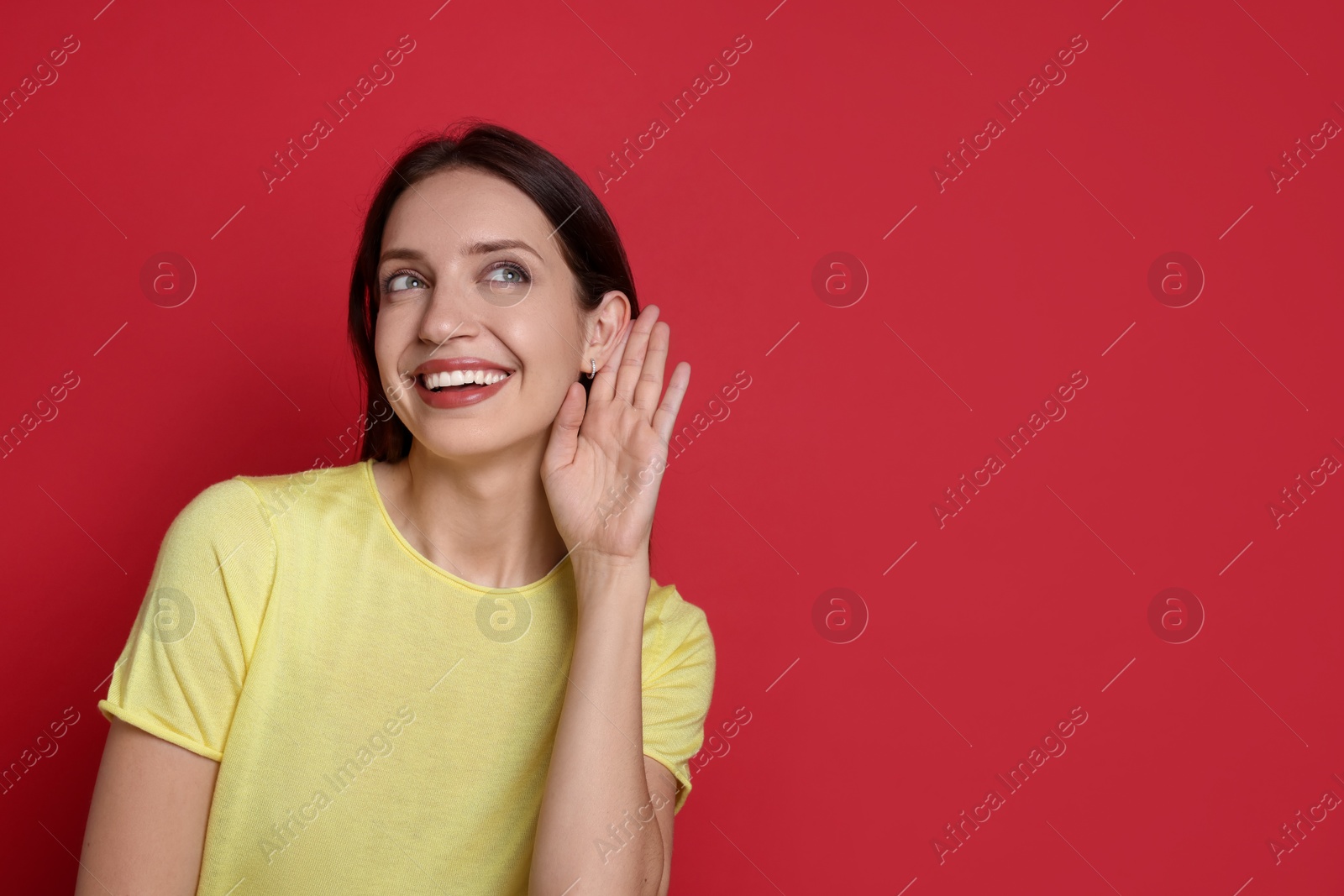 Photo of Woman showing hand to ear gesture on red background, space for text