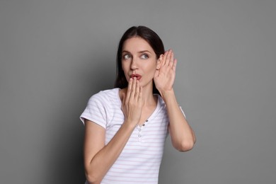 Photo of Woman showing hand to ear gesture on grey background