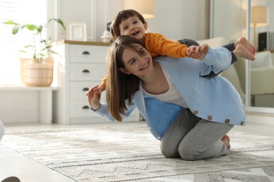 Photo of Happy mother playing with her little son at home. Space for text