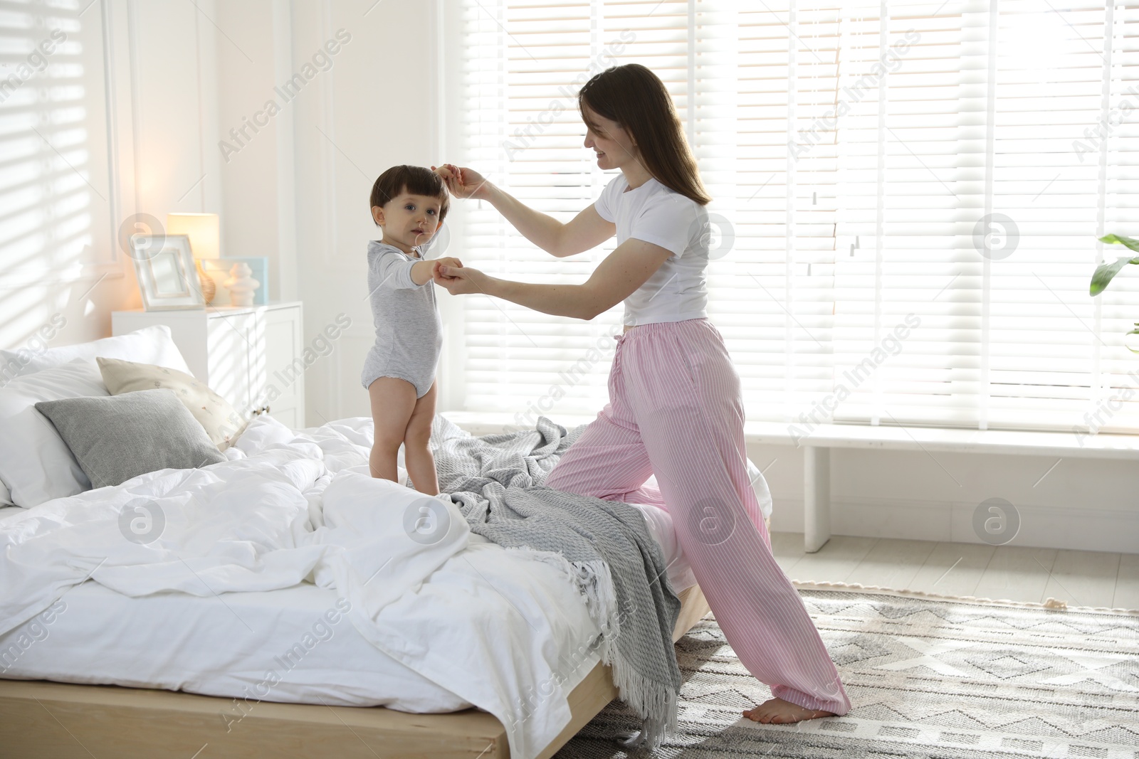 Photo of Happy mother playing with her little son in bedroom