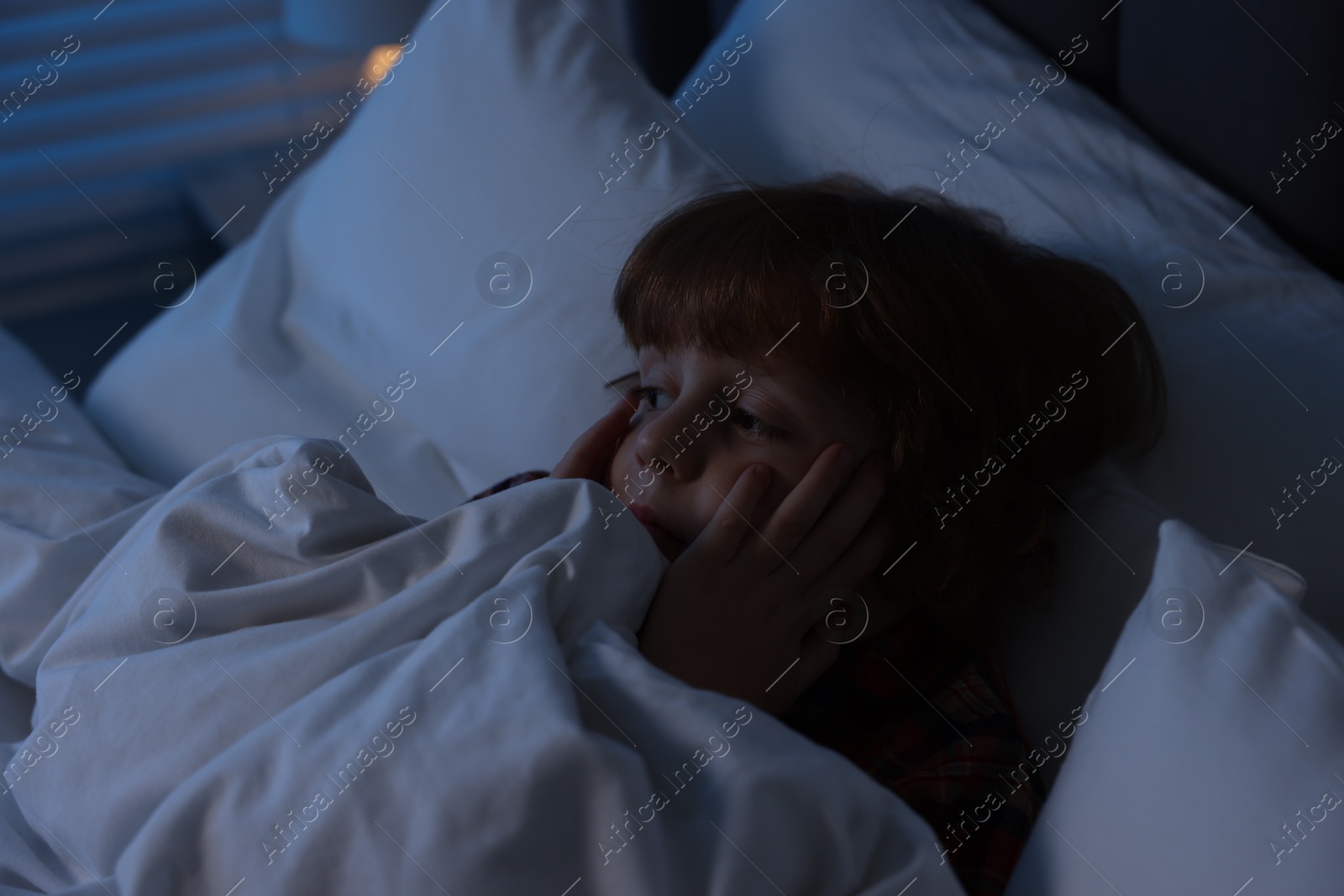 Photo of Scared boy lying in bed at night