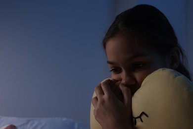 Photo of Fearful girl with pillow in room at night. Space for text