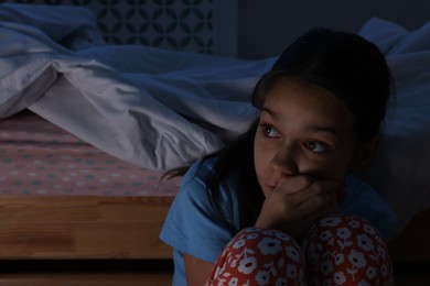 Photo of Afraid girl near bed in her room at night. Space for text