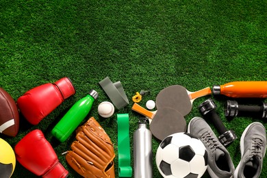 Photo of Different sports equipment on artificial grass, flat lay. Space for text