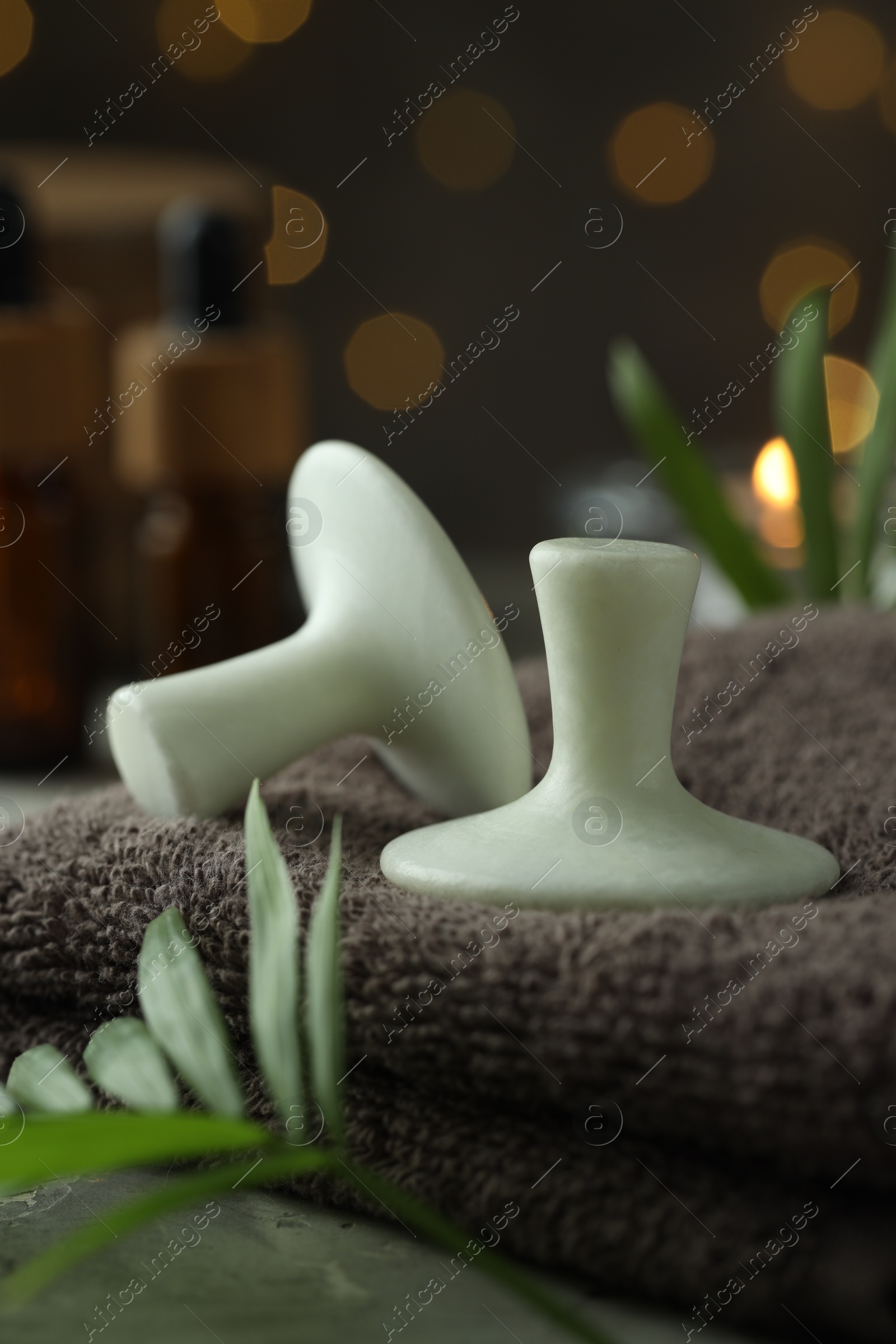 Photo of Spa stones, towel and green leaves on table, closeup