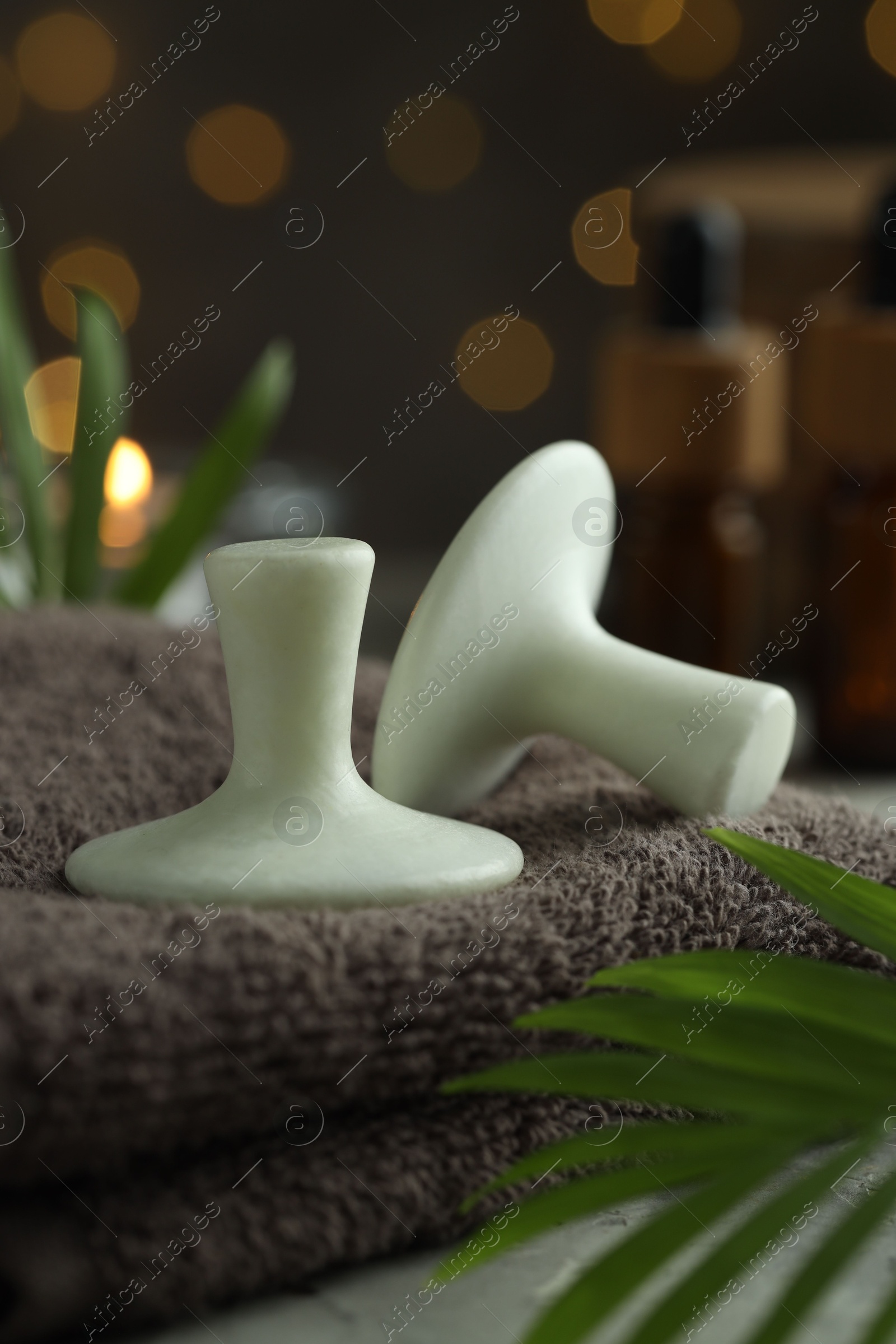 Photo of Spa stones, towel and green leaves on table, closeup