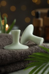 Photo of Spa stones, towel and green leaves on table, closeup