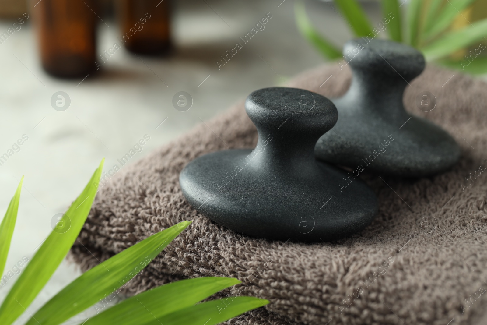 Photo of Spa stones, towel and green leaves on table, closeup