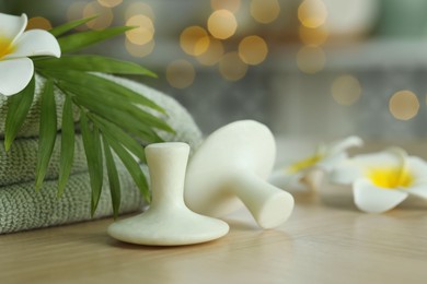 Photo of Spa stones, towel, plumeria flowers and green leaf on wooden table, closeup