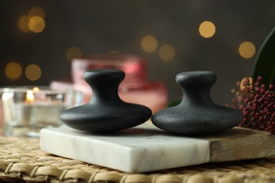 Photo of Spa stones, floral decor and candle on wicker mat, closeup