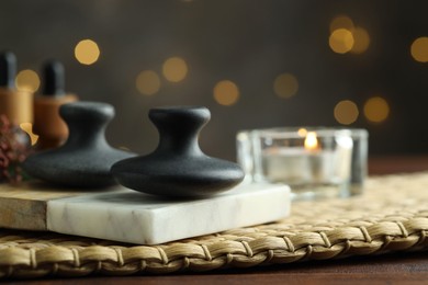 Photo of Spa stones and burning candle on table, closeup