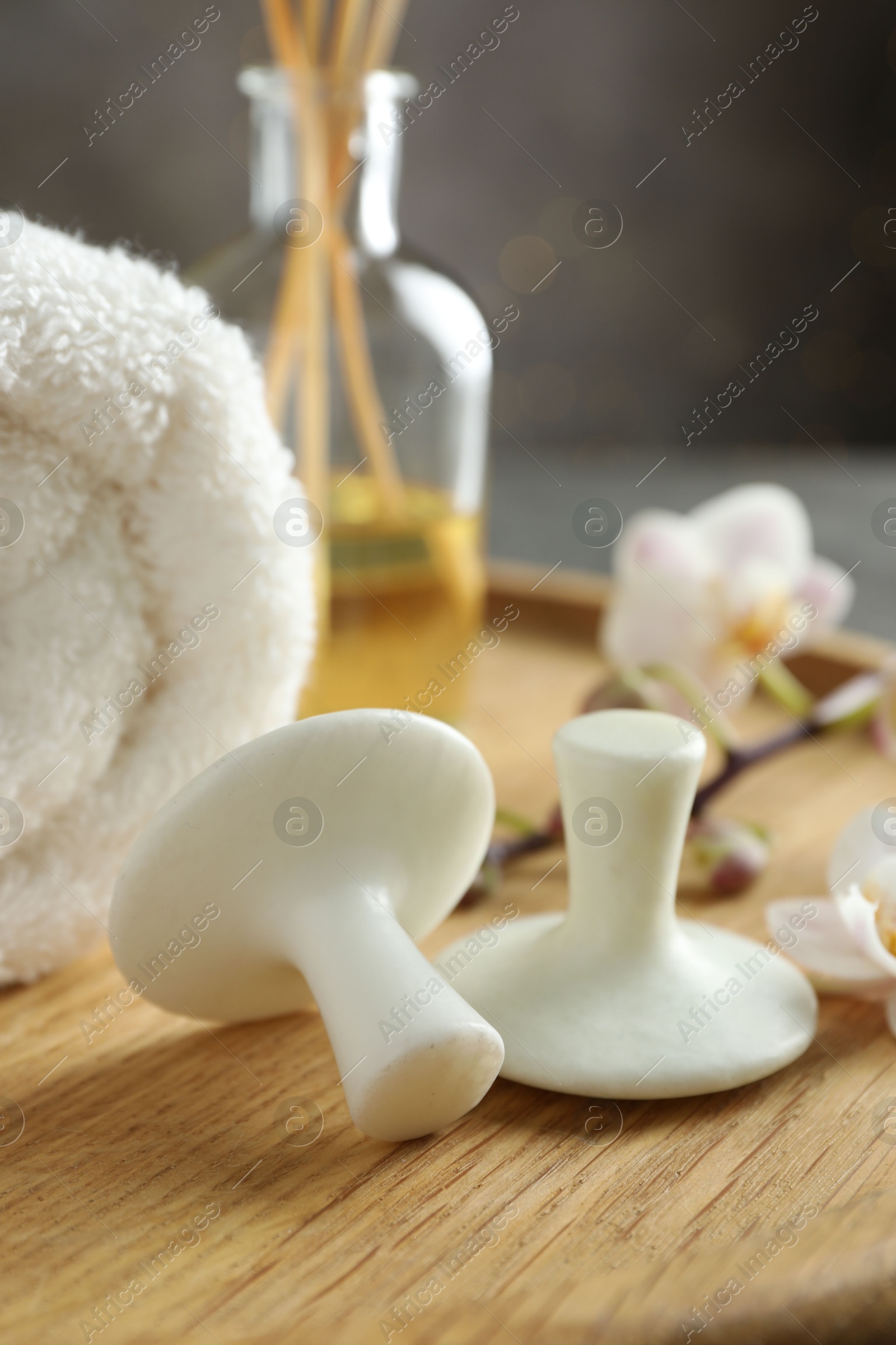 Photo of Spa stones, orchid branch, towel and reed diffuser on wooden tray, closeup