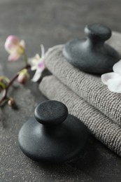 Photo of Spa stones, towels and orchid flowers on grey table, closeup