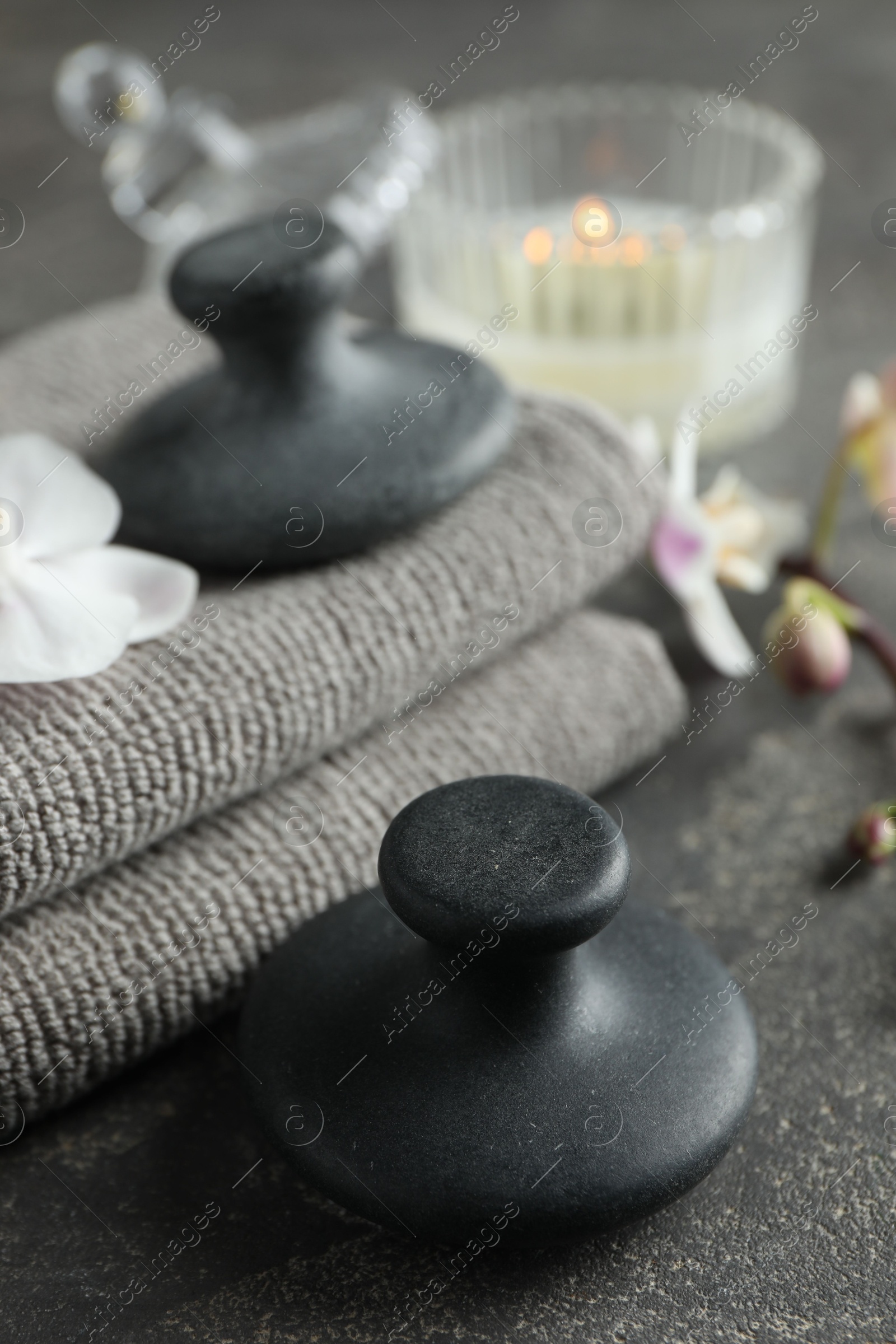 Photo of Spa stones, towels and candle on grey table, closeup