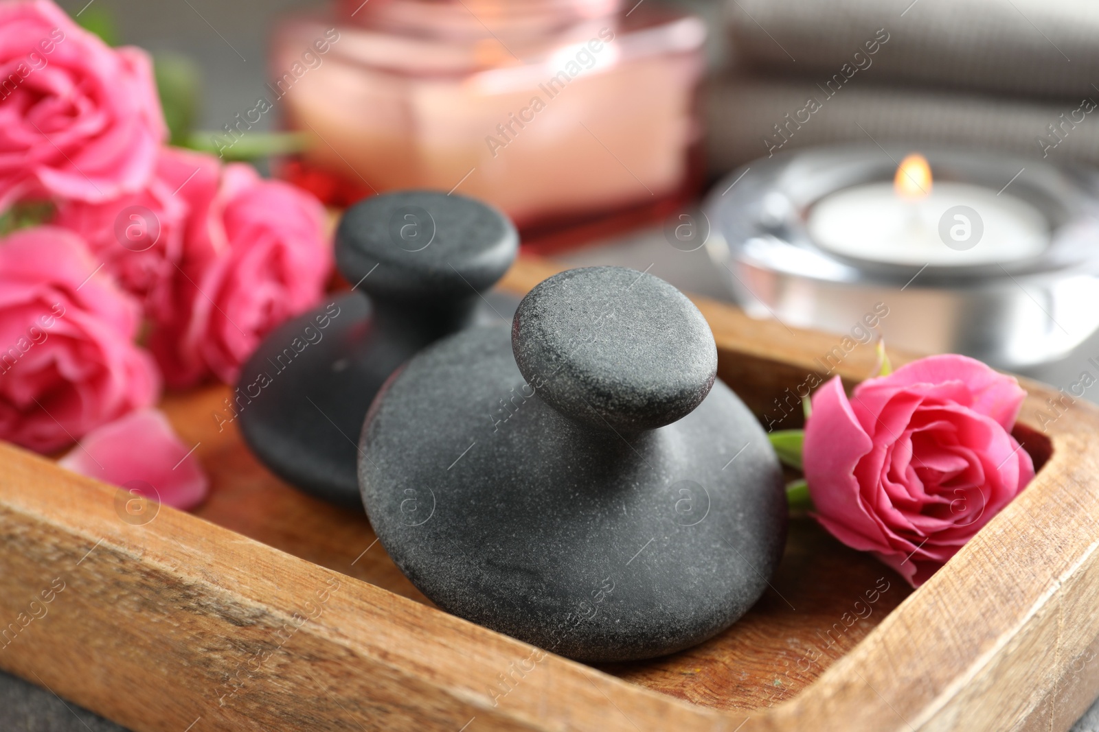 Photo of Spa stones, rose flowers and candles on table, closeup