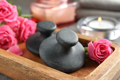 Photo of Spa stones, rose flowers and candles on table, closeup