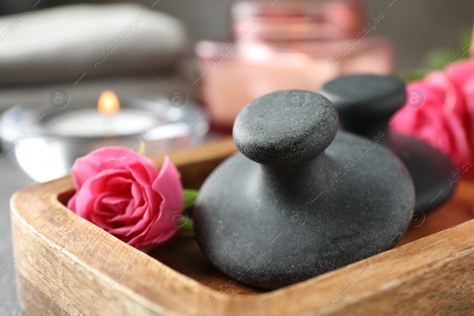 Photo of Spa stones, rose flower and candles on table, closeup