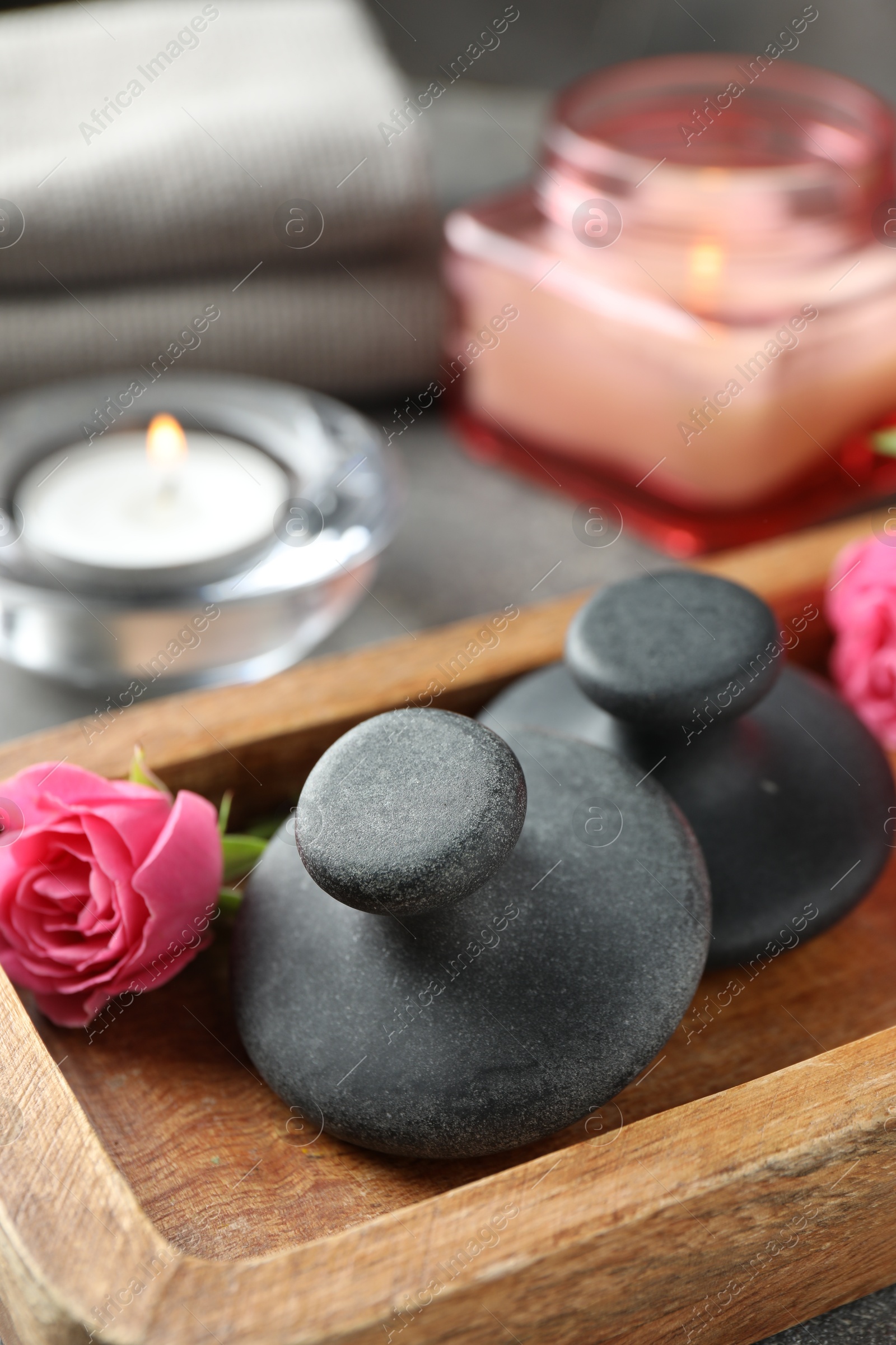 Photo of Spa stones, rose flower and candles on table, closeup